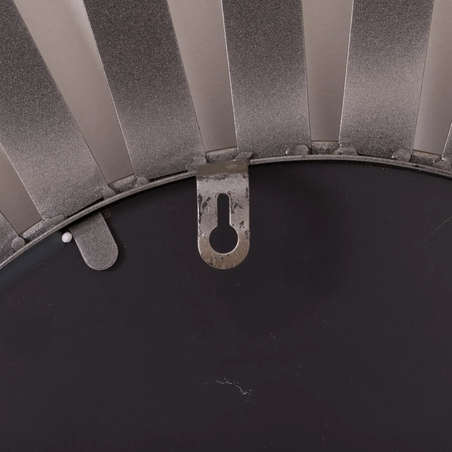 Close-up of a metal wall mirror with a sunburst design and a hanging hook.