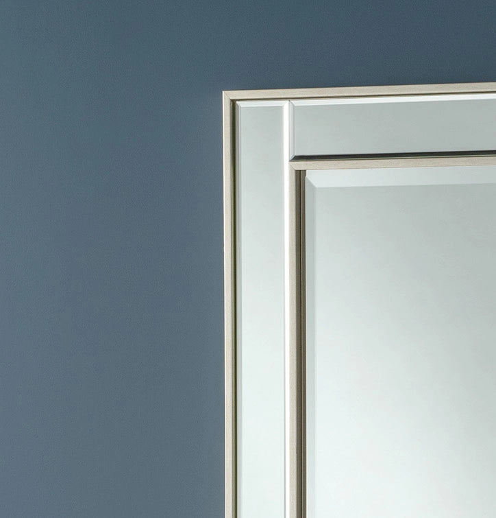 Silver-framed rectangular wall mirror against a dark-grey wall.