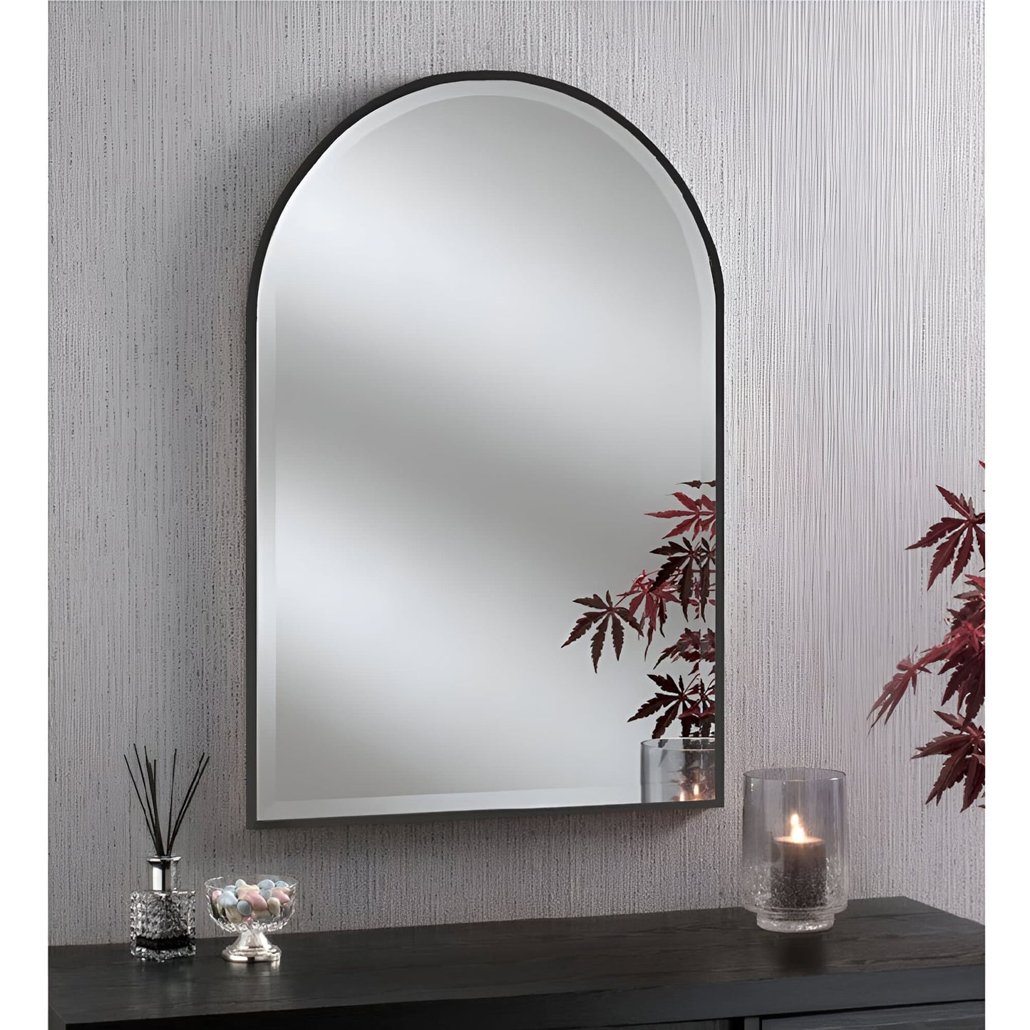Arched black framed bevelled glass mirror on a textured wall, reflecting the room.