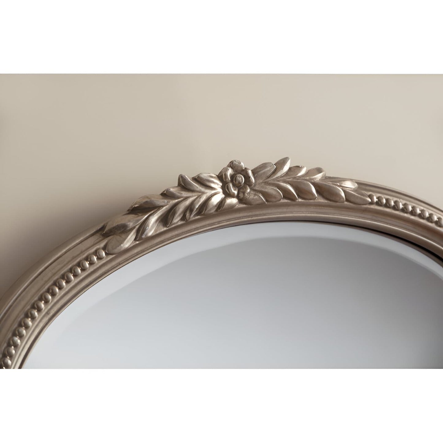 Arched silver-toned wall mirror with ornate floral and leaf-shaped frame.