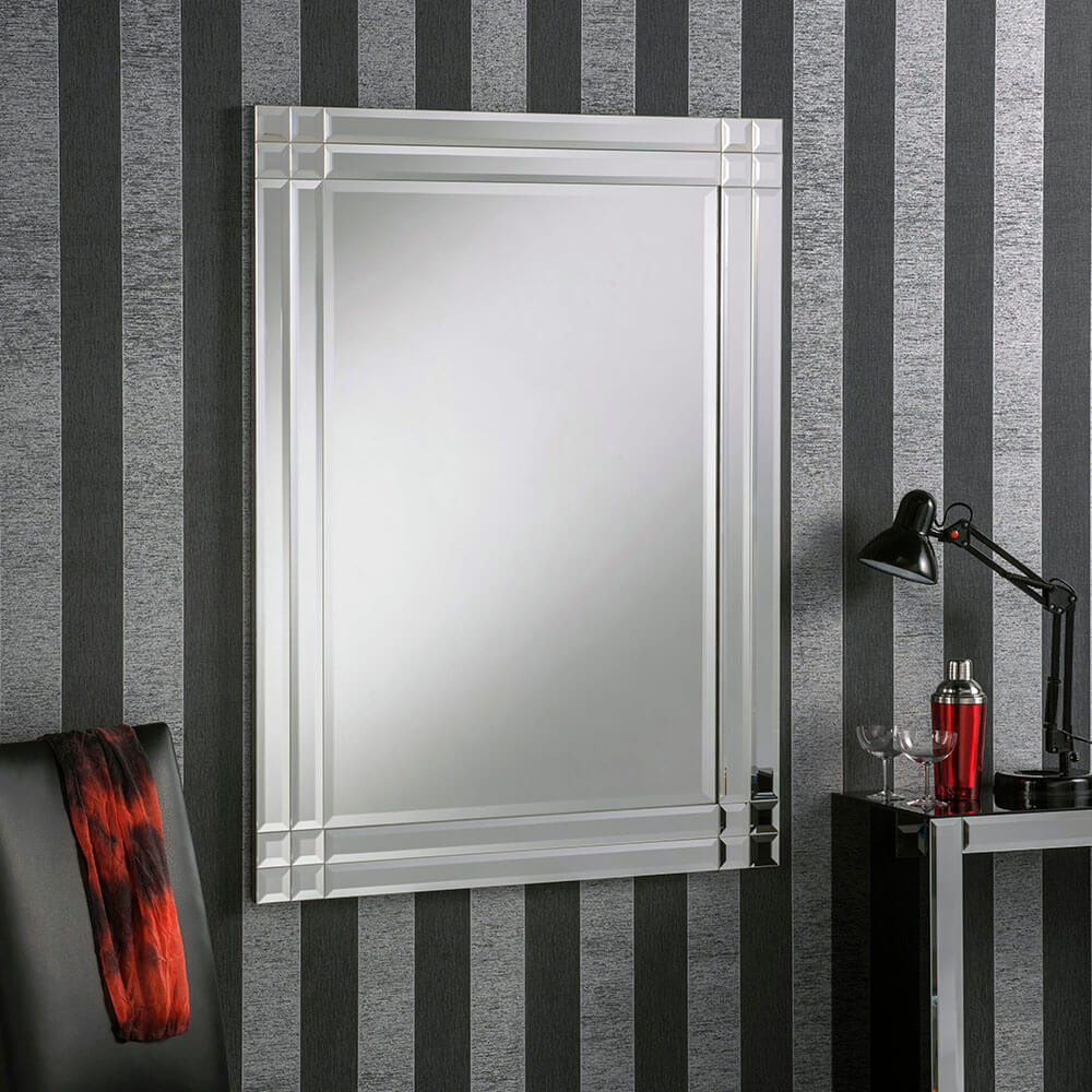 Large rectangular beveled frame mirror with reflective surface, mounted on a striped wallpaper background.