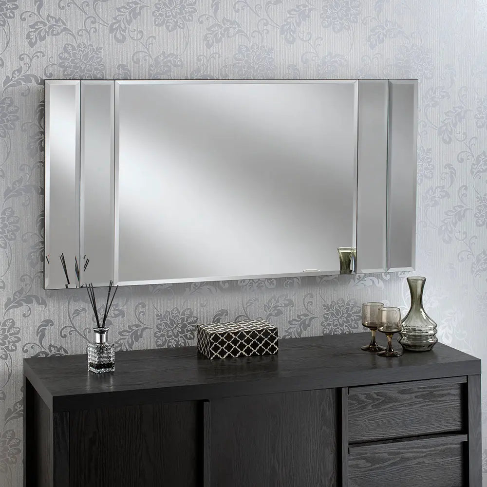 Large, black framed beveled wall mirror with vertical silver dividers, above a dark wood vanity.