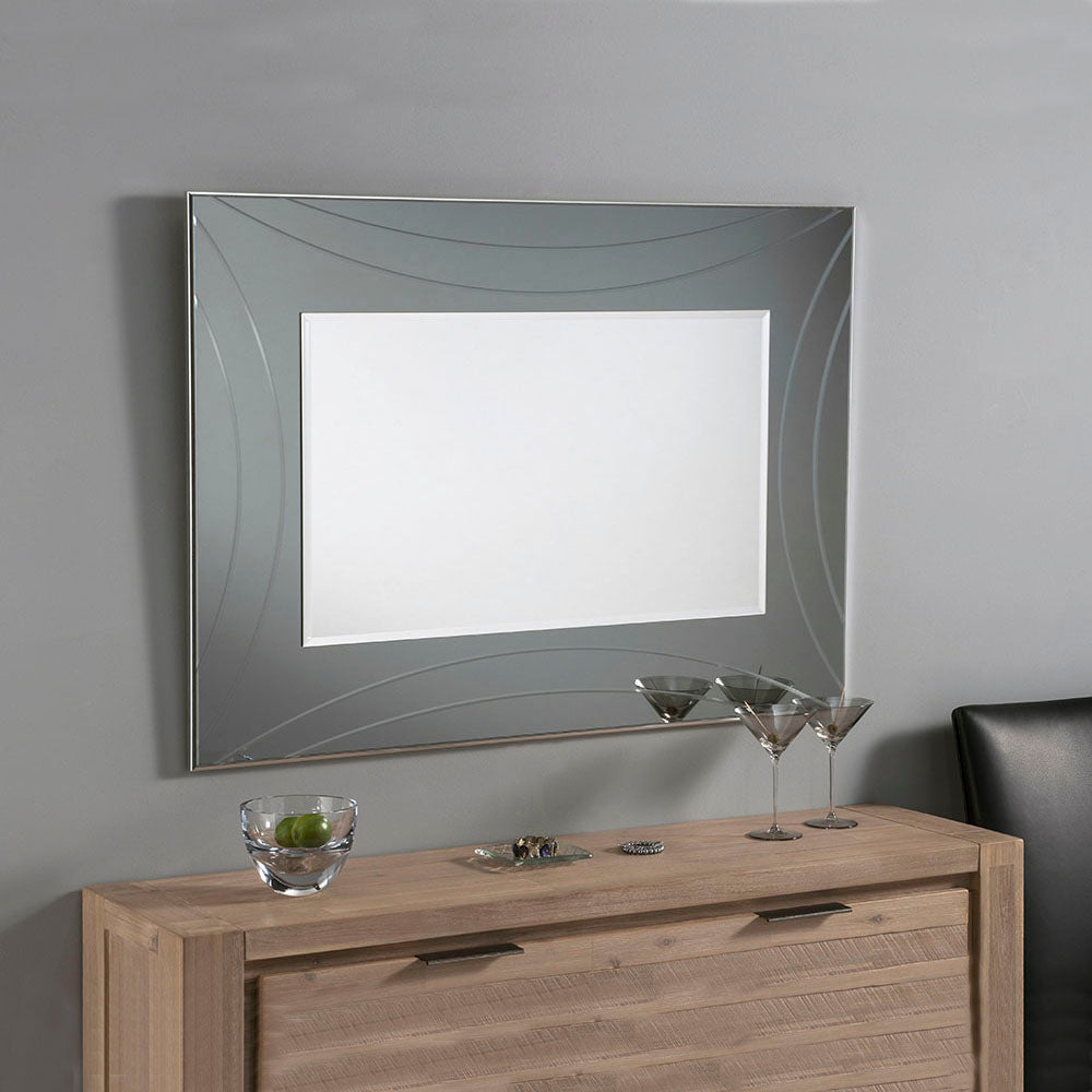Large, framed decorative mirror with a grey, curved design, displayed above a light brown wooden dresser.