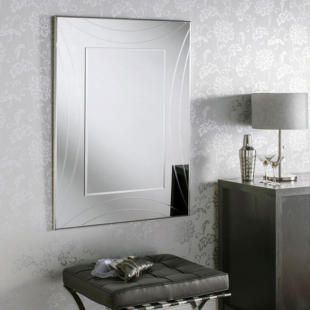 Large, beveled silver framed mirror with a floral wallpaper background.