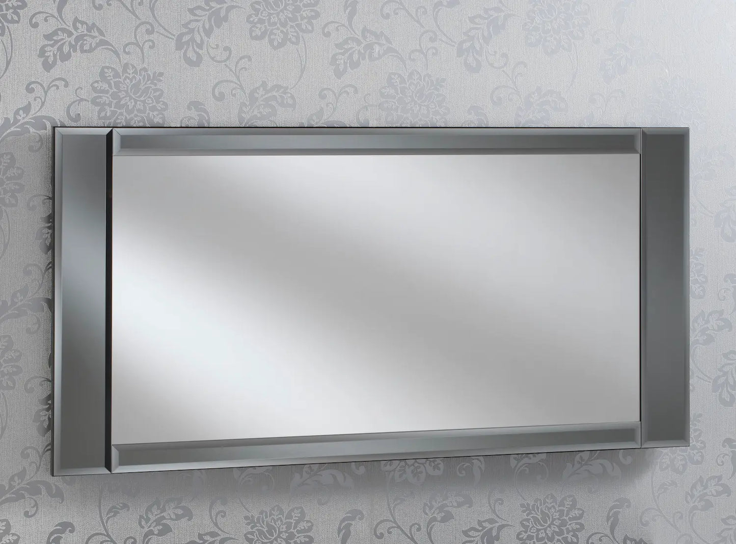 Large rectangular wall mirror with a dark frame, hung against a wallpaper with a floral pattern.