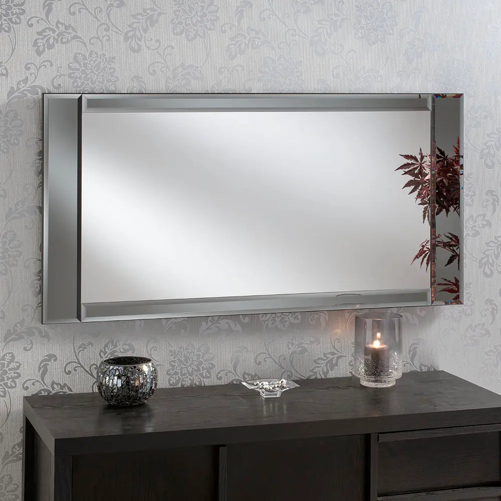 Large rectangular framed mirror on a dark wooden console table with decorative items.