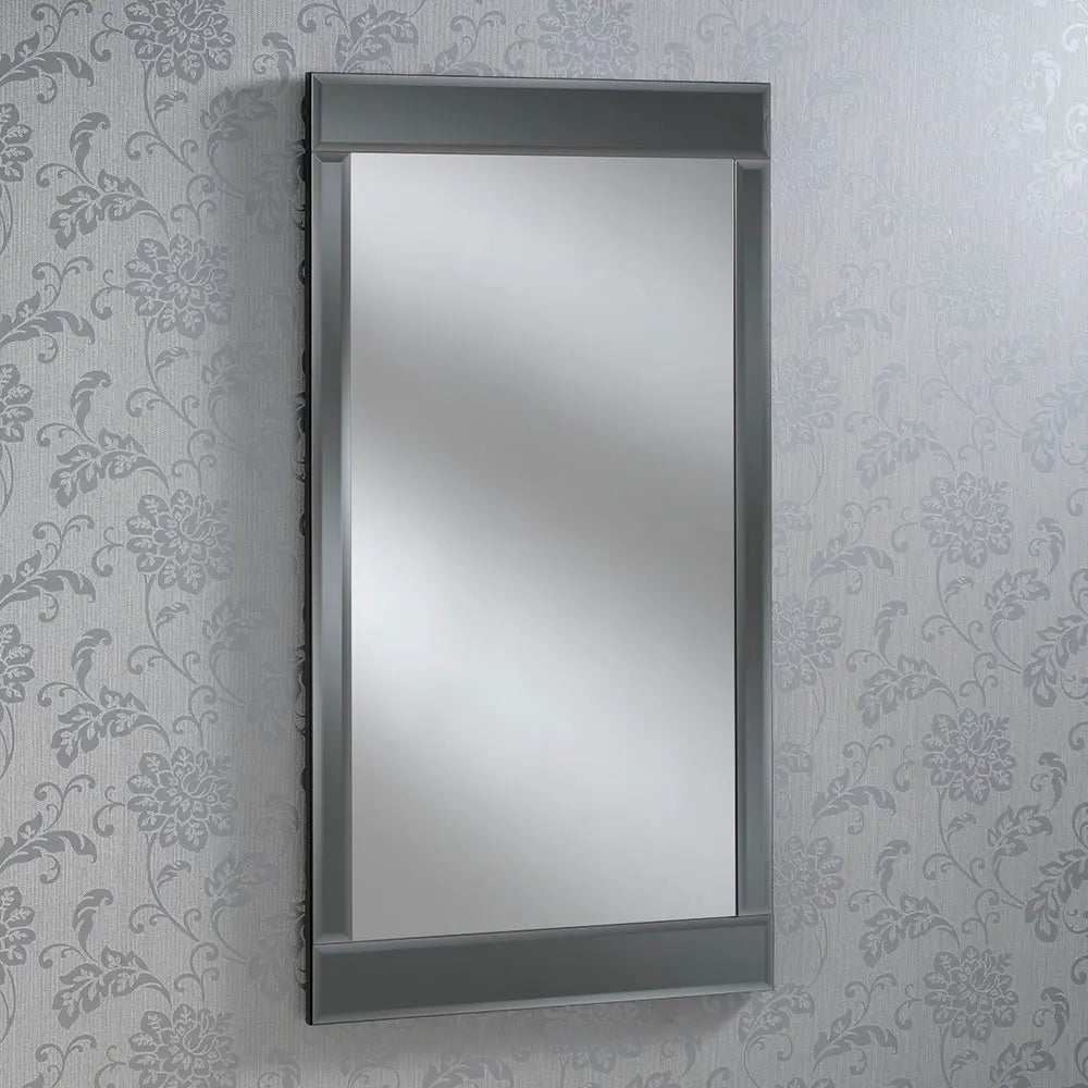 Beveled framed rectangular wall-mounted mirror against a floral wallpaper.