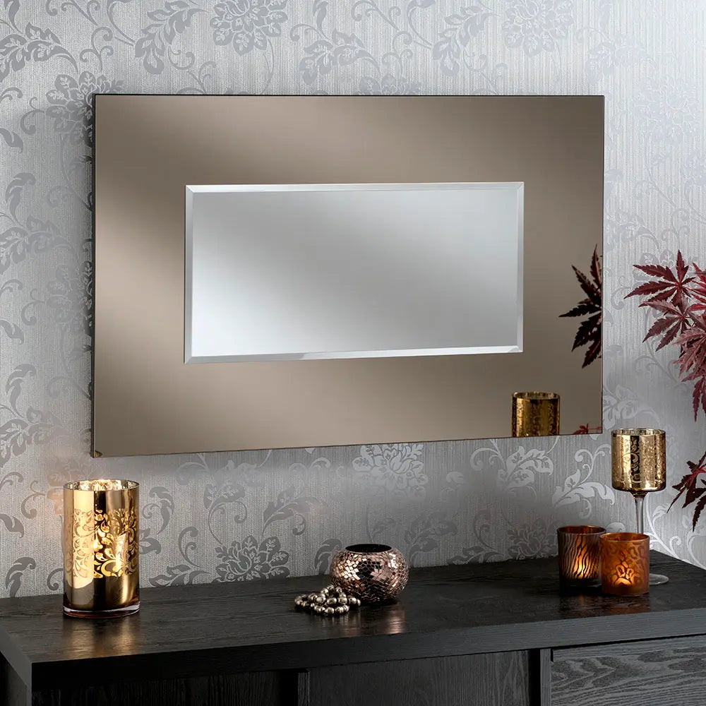 Bronze framed mirror with a rectangular beveled reflective surface, displayed on a dark wood console table with decorative accents.