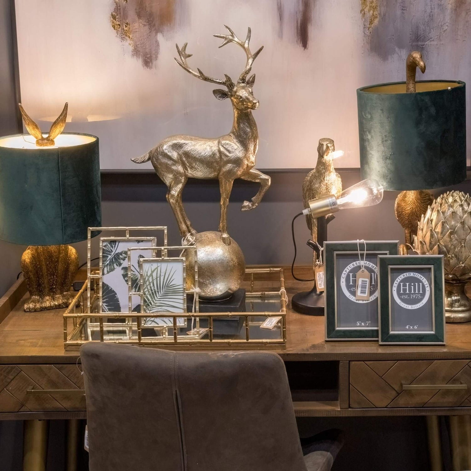 Mirrored Accessories Collection - Gold deer sculpture, mirrored trays, and picture frames on a wooden desk.
